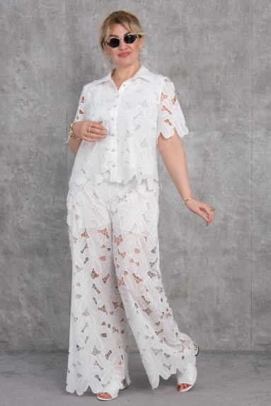  This plus-size womens two-piece suit is presented in a stunning white color. The fabric composition is 65% Cotton, 30% Polyester, and 5% Elastane, offering comfort and flexibility. The top features short sleeves and buttons, with an elegant design. The bottom part has wide legs and a modern cut, both pieces being detailed with floral patterns. Available sizes are 42, 44, 46, and 48.
