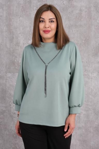  This elegant Plus Size womens blouse shines in petrol green. It is available in sizes 50, 52, 54, and 56, offering a wide range of options. The fabric content is 75% polyester, 20% cotton, and 5% lycra, making it both soft and stretchable. The front features a decorative accessory, and the cuffs have a balloon sleeve style. Its simple and chic design makes it suitable for everyday wear.