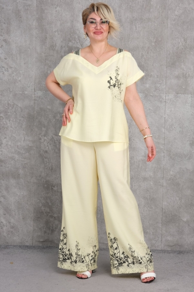  This product is a plus size womens two-piece suit. The suit is elegant yellow and offers a very stylish look. It comes in sizes 42, 44, 46, and 48. The fabric content is 95% cotton and 5% lycra, making the product comfortable and flexible. The top piece stands out with its modern cut and shoulder details, while the bottom piece offers an elegant look with wide legs and a patterned hem.